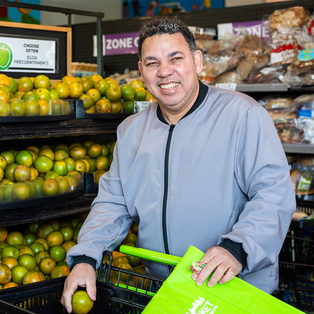 Smiling shopper with a reusable bag in a supermarket.